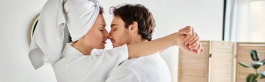 Happy couple in bathrobes kissing in love cuddling in the bathroom, woman with towel on head, banner clipart