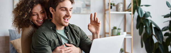 В своей уютной спальне кудрявая молодая женщина и брюнет разговаривают онлайн на ноутбуке, баннер