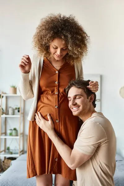 stock image Lovely couple waiting for baby. Handsome smiling happy man listening to baby hugging belly of wife