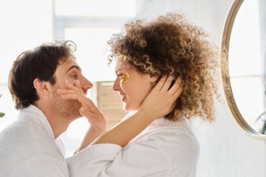 Portrait of happy couple with eye patches  hugging in bathroom and smiling, looking at each other clipart