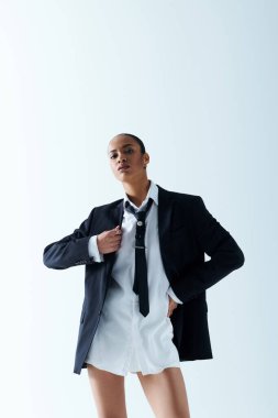 Sivri takım elbiseli ve kravatlı şık bir kadın fotoğraf için poz veriyor..