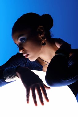A young African American woman delicately places her hands on a bright object clipart