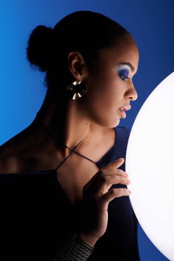 Young African American woman delicately cradling a white sphere in her hands. clipart