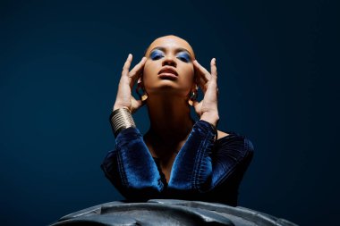 A young African American woman with a striking blue eye makeup captured in a studio setting. clipart