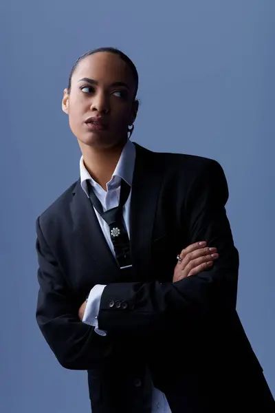 stock image A young African American woman confidently poses in a suit and tie in a photography studio.