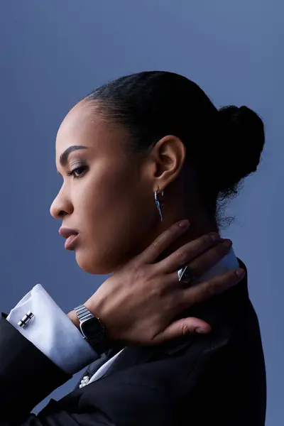 stock image A young African-American woman exudes confidence in a tailored suit with stylish earrings.