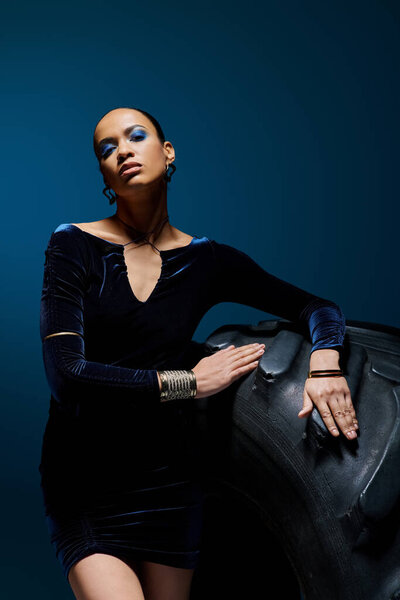 A young African American woman in a black dress elegantly holds a matching black bag.