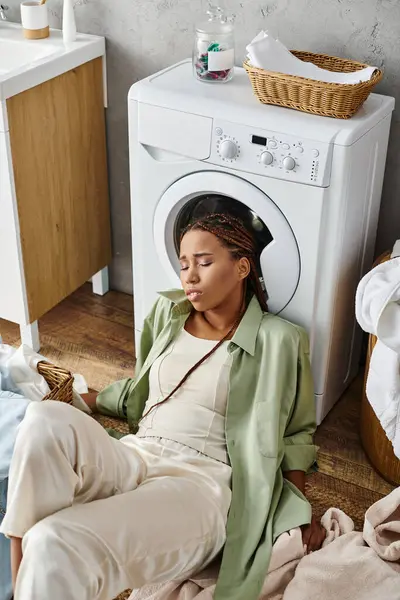 アフリカ系アメリカ人女性 洗濯機の横に座り バスルームで家庭用洗濯をしている — ストック写真