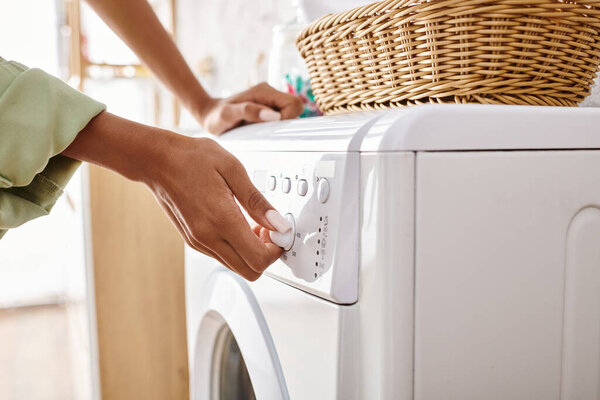 An African American woman loading a dryer onto a washing machine in a bathroom.
