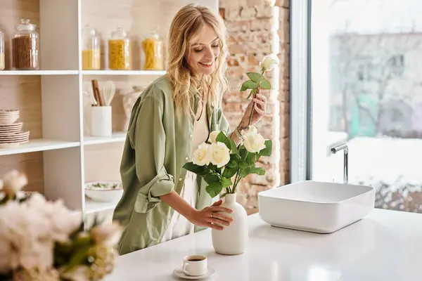 自宅で花瓶にカラフルな花を配置するキッチンの女性 — ストック写真