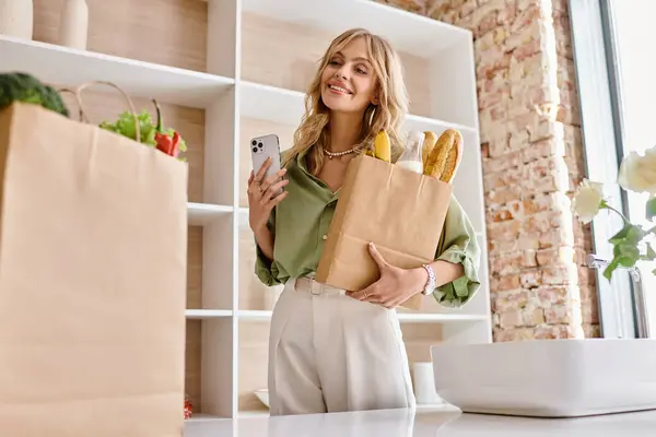 Woman Standing Kitchen Holding Paper Bag Using Cell Phone — Stock Photo, Image