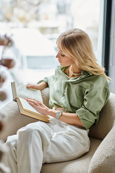 Женщина, сидящая в кресле, погруженная в чтение книги.