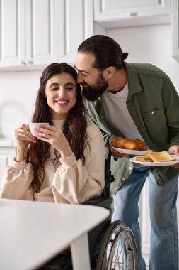 joyous beautiful disable woman in wheelchair enjoying coffee with her husband during breakfast clipart