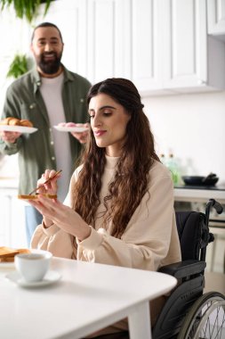 happy attractive woman with disability in wheelchair eating breakfast with her loving husband clipart