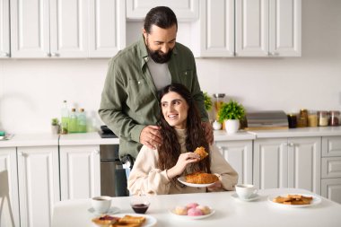 positive man having great time at breakfast with his beautiful disabled wife that eating croissant clipart