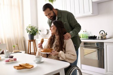 cheerful man having great time at breakfast with his beautiful disabled wife that eating croissant clipart