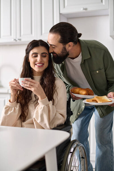 joyous beautiful disable woman in wheelchair enjoying coffee with her husband during breakfast