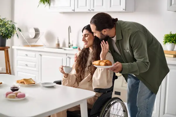 坐在轮椅上的快乐美丽的残疾妇女在早餐时和丈夫一起喝咖啡 — 图库照片