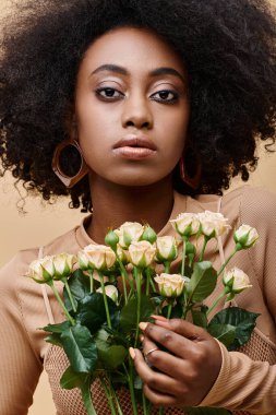 Genç ve kıvırcık Afrikalı 20 'li yaşlardaki Amerikalı kız elinde bej arka planda minik güller, şeftali tüyü