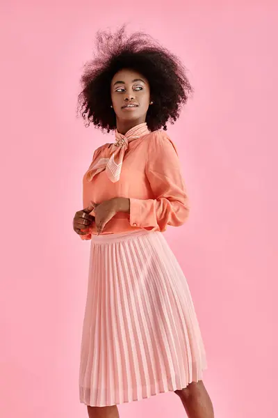 身穿桃色衬衫 裙子和领巾的卷曲的非洲裔美国女人 在粉红的背景上摆姿势 — 图库照片