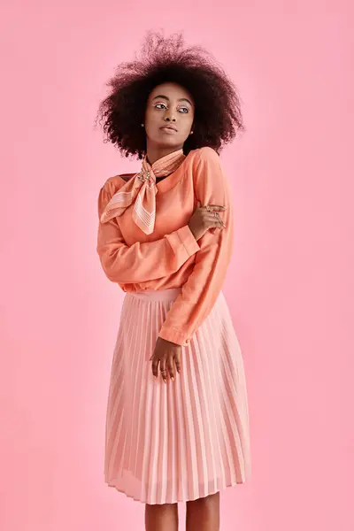 身穿桃衫 迷你裙和脖子围巾的卷曲的非洲裔美国妇女 背景为粉色 — 图库照片