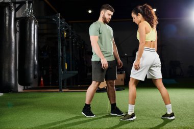 Bir erkek antrenör, spor salonunda bir kadına savunma teknikleri öğretir..