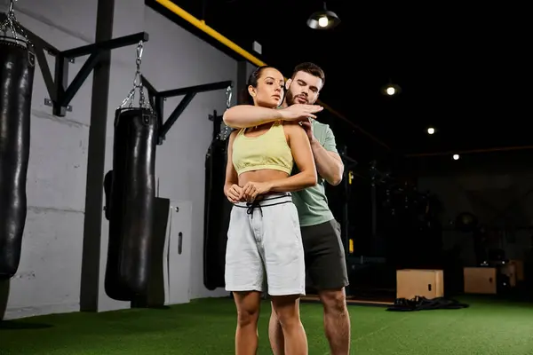 Stock image A male trainer guides a woman in mastering self-defense techniques in a gym, showcasing strength and empowerment.