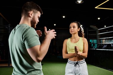 A male trainer demonstrates self-defense techniques to a woman in a gym, focusing on empowerment and skill-building. clipart
