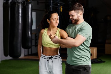 A male trainer demonstrates self-defense techniques to a woman in a gym setting, emphasizing safety and empowerment. clipart