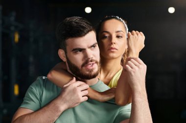 Bir adam, bir savunma antrenörü, bir kadını kollarında tutuyor, spor salonunda bir tekniği gösteriyor..