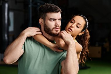 Bir kadın spor salonunda bir erkekle savunma eğitimi alıyor..