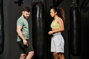 Bir erkek antrenör, spor salonunda bir kadına savunma teknikleri öğretir..