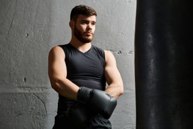 Yakışıklı sakallı adam boks yapıyor, spor salonunda kum torbasının yanında duruyor..