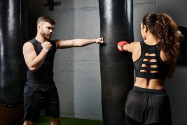 Erkek bir antrenör, esmer bir sporcuya sıkı bir antrenman sırasında boks ringinde antrenman yaparken rehberlik eder..