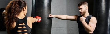 Erkek bir antrenör, spor salonunda boks yaparken esmer bir sporcuya rehberlik eder..