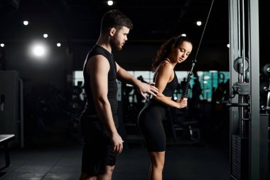 Kişisel antrenör, spor salonunda esmer bir sporcuyla çalışıyor. Egzersiz yapıyor ve rehberlik ediyor..