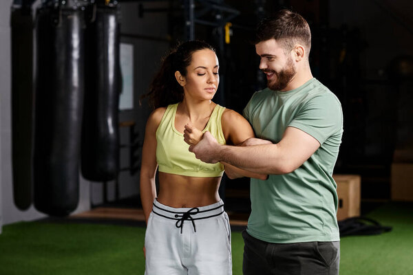 A male trainer demonstrates self-defense techniques to a woman in a gym setting, emphasizing safety and empowerment.