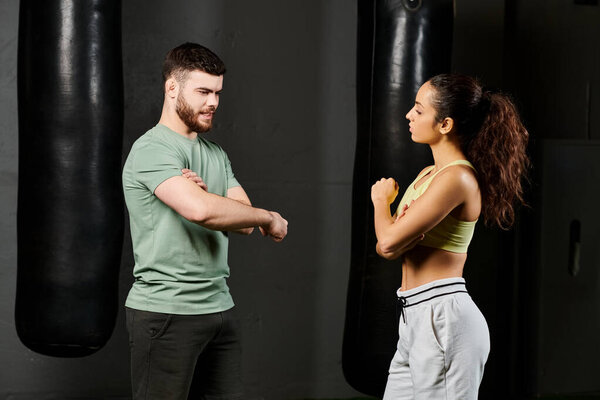 Male trainer teaches self-defense techniques to woman in gym.