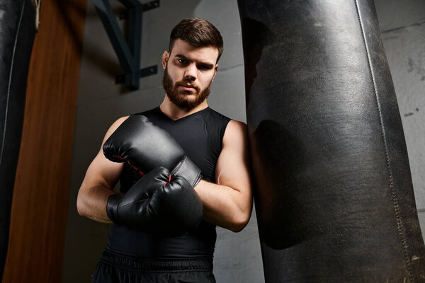 Красивый бородатый мужчина в спортзале, наносит удары по боксерской груше с решимостью и сосредоточенностью.