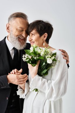 Gelinlik giymiş orta yaşlı bir gelin ve damat, stüdyo ortamında özel günlerini kutluyorlar..