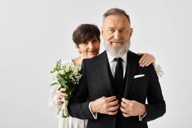 Siyah beyaz düğün kıyafetleri içinde orta yaşlı gelin ve damat stüdyo ortamında özel günlerini kutluyorlar..