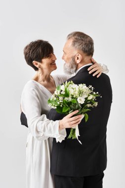Gelinlik giymiş orta yaşlı bir gelin ve damat, stüdyo ortamında özel günlerini kutluyor..