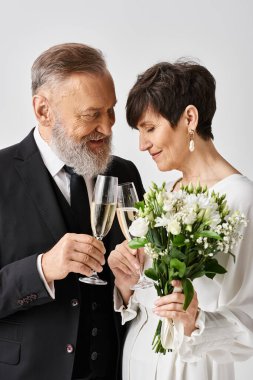 Düğün kıyafetli orta yaşlı gelin ve damat neşe dolu bir kutlama için ellerinde şampanya kadehleriyle..