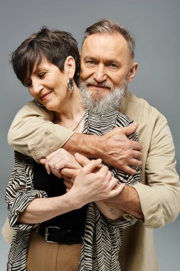 Orta yaşlı şık giyinmiş bir çift stüdyo ortamında birbirlerine nazikçe sarılıyorlar..