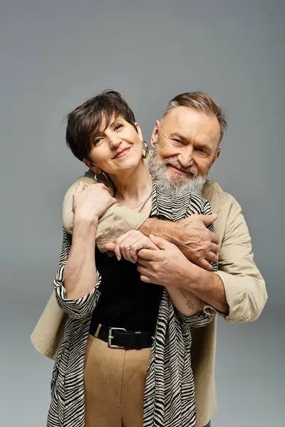 stock image Middle-aged couple in stylish attire sharing a warm, tender hug in a studio setting, expressing love and connection.