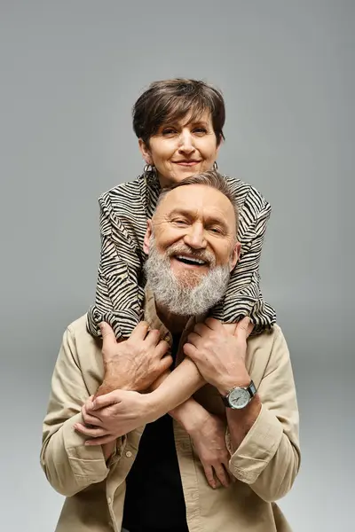 stock image A middle-aged man holding a woman on his shoulders in a stylish studio setting.