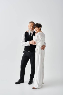 Orta yaşlı bir gelin ve damat zarif bir şekilde poz verir, özel bir olayı kutlarken mutluluk ve aşk yayar..