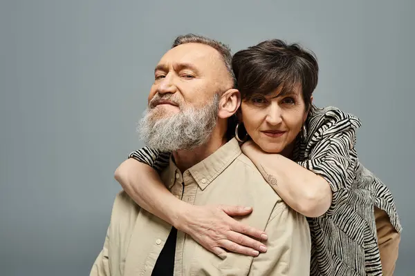 stock image A middle-aged man with a beard tenderly hugs a woman in stylish attire in a studio setting.