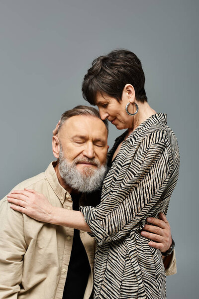 Пара средних лет, элегантно одетые, нежно обнимающие друг друга в изысканной студии.