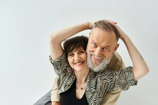 stock image A middle-aged man and woman, stylishly dressed, strike a pose together in a studio setting.